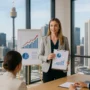 A professional woman presenting growth charts in a Sydney office with city skyline in the background, symbolising business growth strategies in Australia.